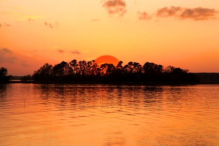 Bright orange sky with Sun set over island の写真素材