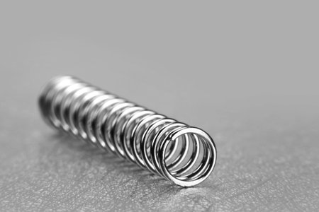 Small tiny metal spring on grey background