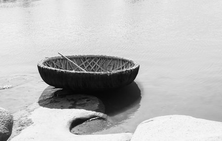 Tungabhadra River at Hampi. In the foreground is a round boat in monochrome.