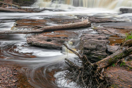 Running water over rocks  at Manido falls with dead trees in the water in rural Michigan upper peninsulaの写真素材