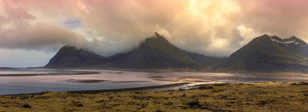 Mountains at Icelandic sea shore with dramatic cloudy sky under twilight.の写真素材