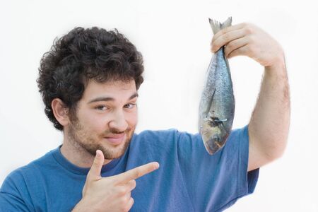 Satisfied man holding a fish, pointing it with a finger. Isolated on white. White caucasian.の写真素材