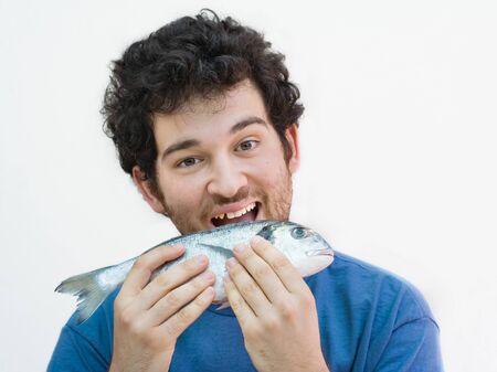 Young man biting a fish. Curly hair with beard. White caucasian. Isolated on white.の写真素材