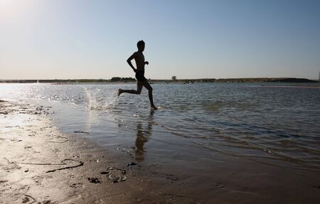 Running man on the beach, water, sea, sunの写真素材