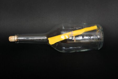 Yellow paper, message in a bottle, cover, black backgroundの写真素材