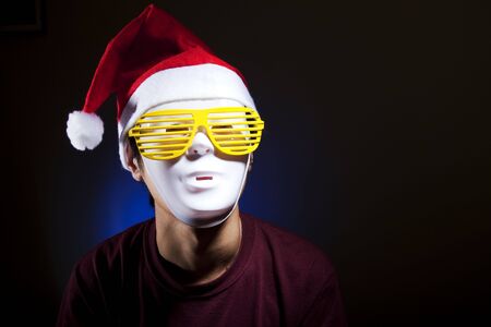 Santa, men in white mask yellow glasses and red hatの写真素材