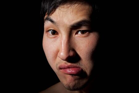 The obverse portrait of the young Asian man which poses a mugの写真素材