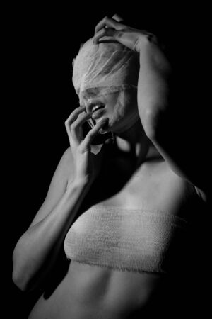 The bared girl wound with bandage emotional portraits on a black backgroundの写真素材