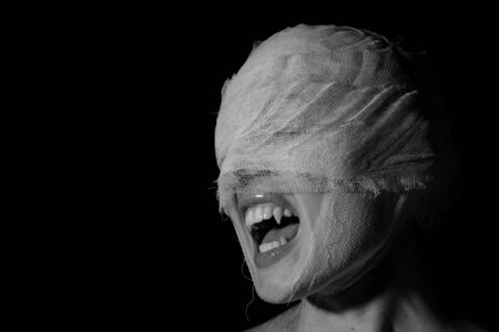 Girl's face wound with bandage with a teeth as at the vampire on a black backgroundの写真素材