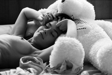 The beautiful girl naked sleeps on the favourite teddy bearの写真素材