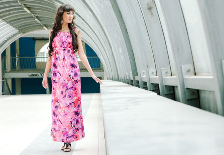 The beautiful girl in a long dress is by the window in a pedestrian crossingの写真素材