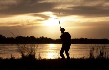 The silhouette of the guy with a fishing tackle, at sunset, which fishes
の写真素材