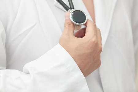 Hand man in a white lab coat holding a stethoscopeの写真素材