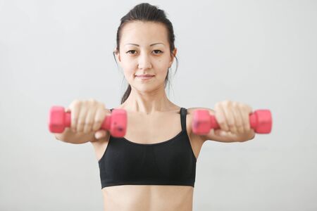 The girl in sportswear is engaged in the gym with dumbbellsの写真素材