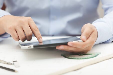 Hands of the man in the blue shirt are holding a tablet computerの写真素材