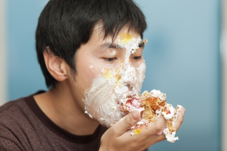 Men eating a piece of cake smeared with creamの写真素材