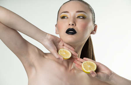Beauty portrait of a girl with lemon on a white backgroundの写真素材