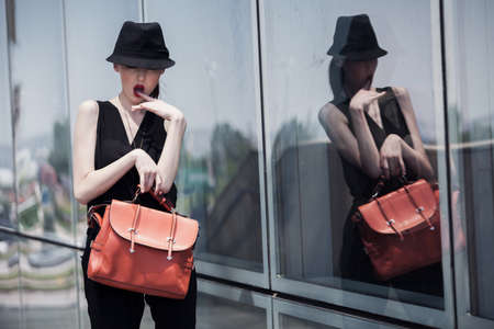 Stylish asian girl in a black suit and hat, posing with a glass wallの写真素材