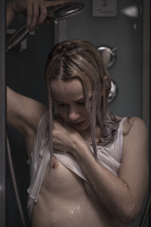 The seminude girl poses in a shower boothの写真素材