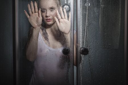 The seminude girl poses in a shower boothの写真素材