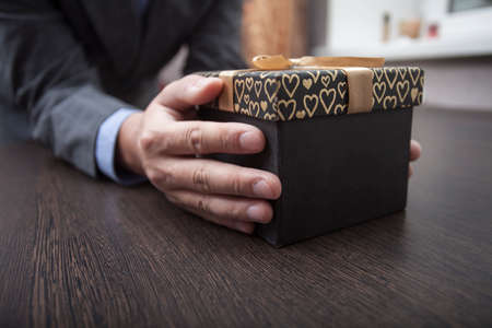Man's hands keep a box in a business suit wrapped up by a bowの写真素材