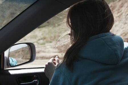 The European girl goes in the car having put out the head in a windowの写真素材