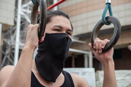 The guy is pushing up on the bars, in a black T-shirt and mask, in quarantineの写真素材