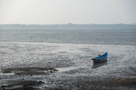 An old abandoned rowboat in shallow water, Goa, Indiaの写真素材
