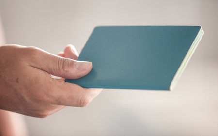 Close-Up Of Cropped Hand Holding Passport Against Clean Blurred Backgroundの写真素材