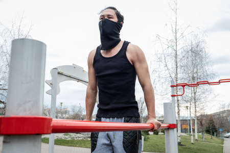 The guy is pushing up on the bars, in a black T-shirt and mask, in quarantineの写真素材
