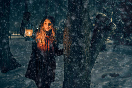Young girl with lantern in winter forest fairy tale, book cover, christmas timeの写真素材