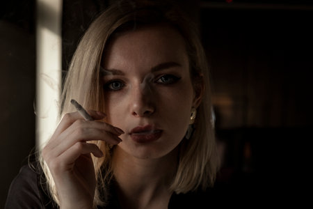 Close-Up Of Young Woman Smoking Cigarette By Windowの写真素材