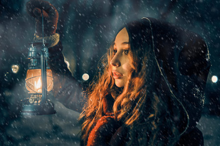 Young girl with lantern in winter forest fairy tale, book cover, christmas timeの写真素材