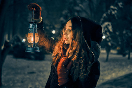 Young girl with lantern in winter forest fairy tale, book cover, christmas timeの写真素材