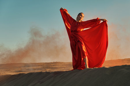 Woman in red dress dancing in the desert at blue skyの写真素材
