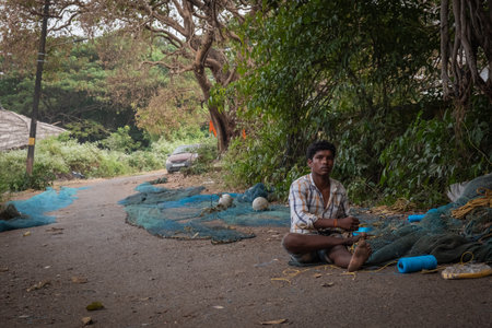 Indian Fisherman repairs fishing net in Goa, Indiaの写真素材