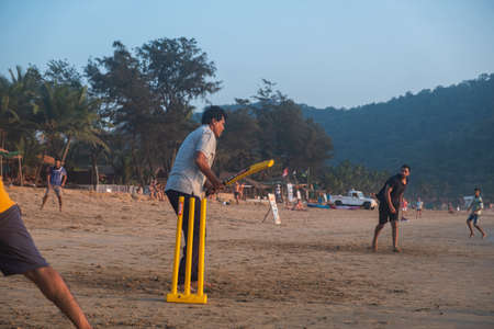 Group of Indian adults playing cricket on beach at sunset, Goa, Indiaの写真素材