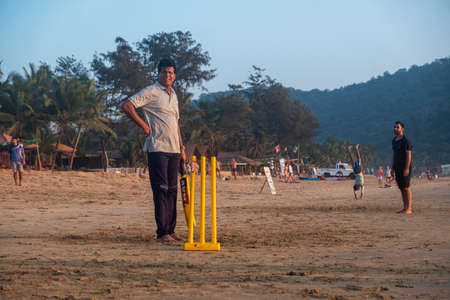 Group of Indian adults playing cricket on beach at sunset, Goa, Indiaの写真素材