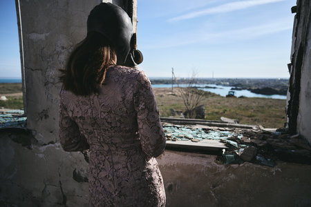 A girl in a gas mask stands in an abandoned building and looks out the windowの写真素材