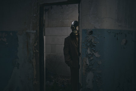 A man in gas mask standing inside an old building, peeking around the corner, good for book coverの写真素材