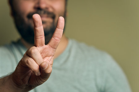 A bearded European man shows hand sign victoryの写真素材