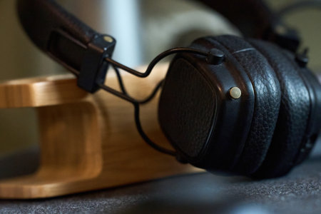 Black over-ear headphones sit elegantly on a sleek wooden stand, highlighting their modern design and craftsmanship in a cozy space.の写真素材