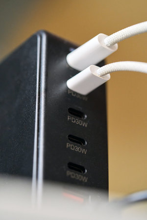 Two charging cables are connected to a charging station with multiple USB-C ports. The station is...