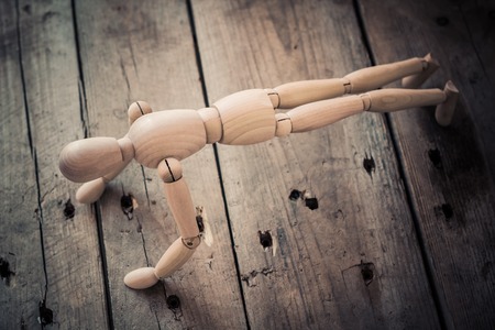 Wooden figurine practicing crank on an old wooden table.の写真素材