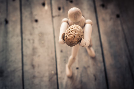 Wooden figure holding walnuts on an old wooden table.の写真素材