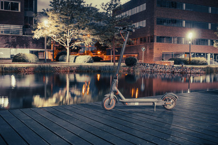 Electric scooter on a wooden pier by the water at night.の写真素材