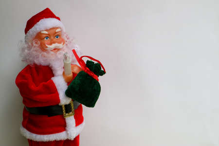 Santa Claus with red hat, green bag full of gifts and candles, Santa Claus toy on a white background, Merry Christmas decoration, New Year's card, winter holidaysの写真素材