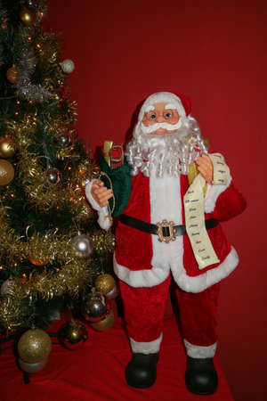 Santa Claus with a white long beard, red hat, glasses and a green bag full of gifts, Santa Claus and Christmas tree with decoration, Santa Claus children's toy , Christmas decoration, New Year's card, Winter holidaysの写真素材