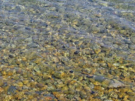 Clear shallow water of a pebble beachの写真素材