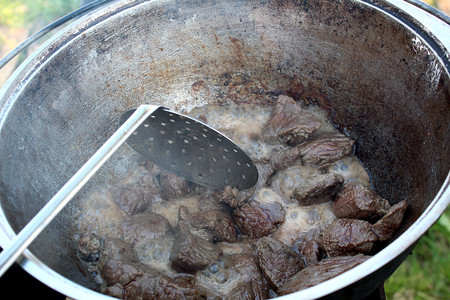 large pieces of meat to boil to the cauldron on the streetの写真素材